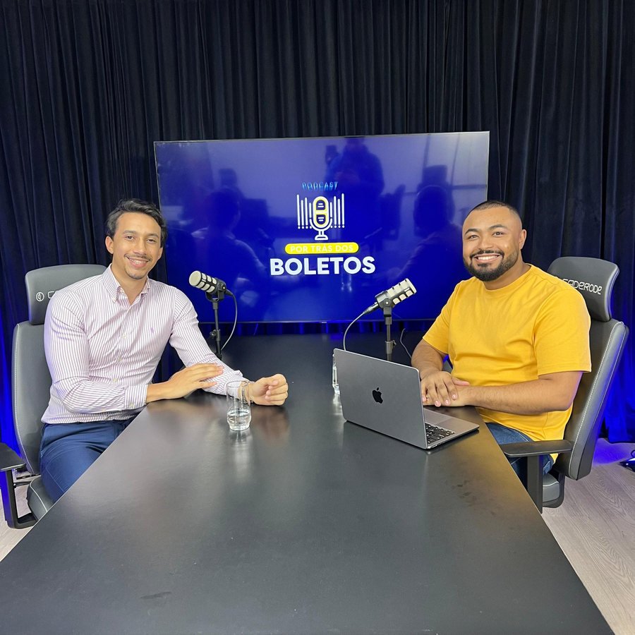 Host e convidado sorrindo à mesa de gravação